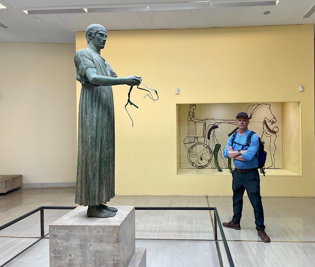 A reprimanded classics professor stands by the charioteer.